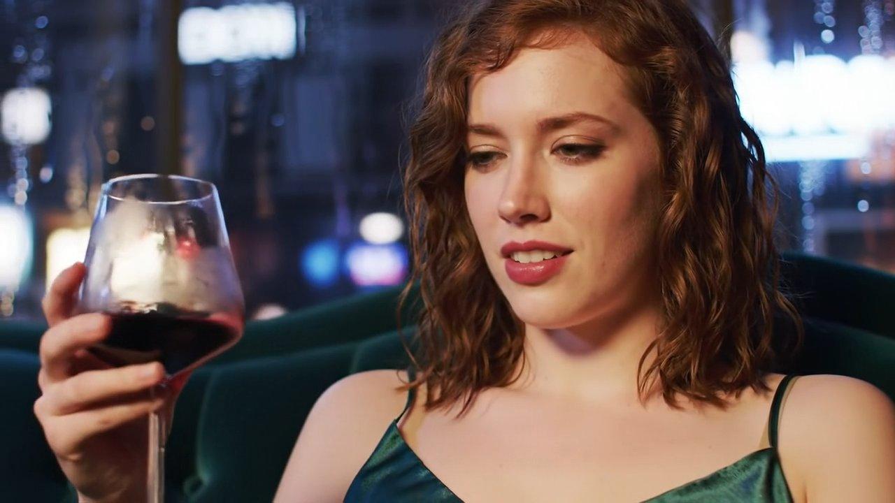 A young woman in a silk slip dress reclines languidly on a vintage velvet sofa